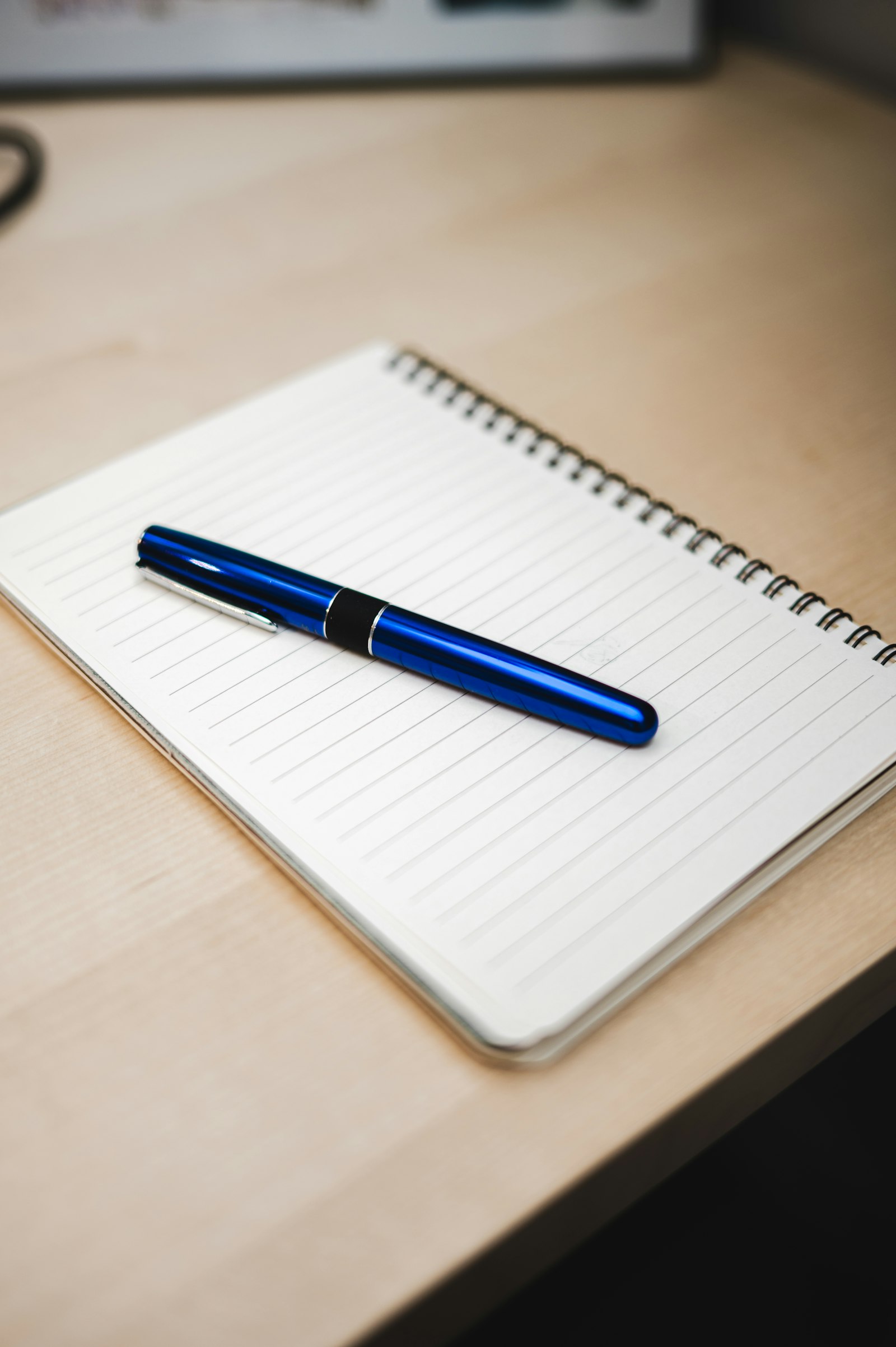 Blauer Stift auf einem Notizbuch auf einem Schreibtisch